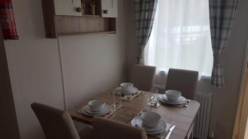 a dining room table with chairs and a wooden table and a window at CCT Caravan in Turnberry