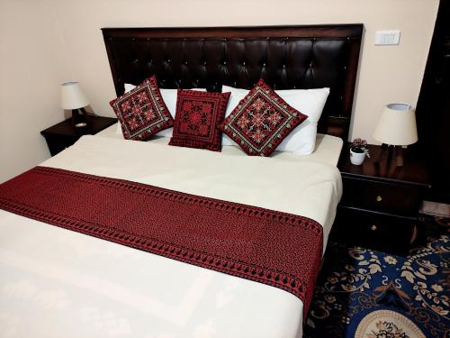 a bedroom with a large bed with red pillows at Majido Hotel in Wadi Musa
