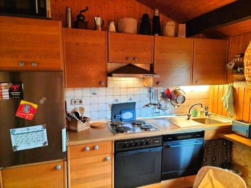 a kitchen with wooden cabinets and a black dishwasher at Ferienhaus am Listersee in Meinerzhagen