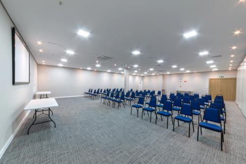 a conference room with blue chairs and a podium at Laghetto Canela in Canela