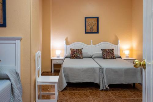 a bedroom with a white bed with two tables and a chair at Sanvi Xerez Centro in Jerez de la Frontera