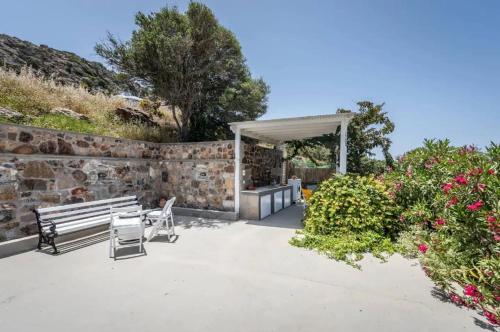 a patio with a bench and a stone wall at Ralaki Cottage in Ralaki