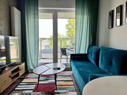 a living room with a blue couch and a large window at PRIMO Premium Apartments Łódź Fabryczna in Łódź