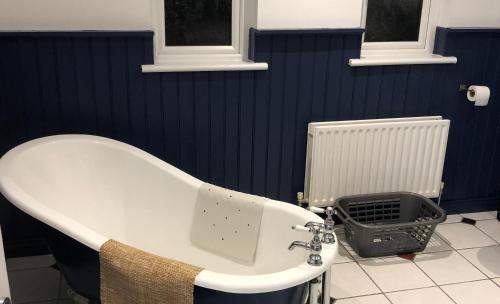 a bath tub in a bathroom with a blue wall at Captivating & Cosy 4-Bedroom House in Magherafelt in Magherafelt