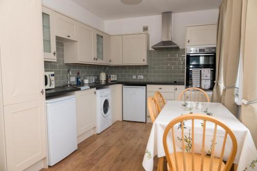 una cocina con armarios blancos y una mesa con sillas. en Bexhill Luxury Sea Stay Flat 2 en Bexhill