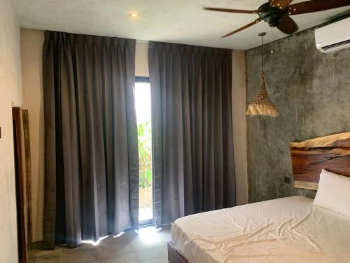 a bedroom with a bed and a large window at Condominio Pacha en Tulum in Tulum