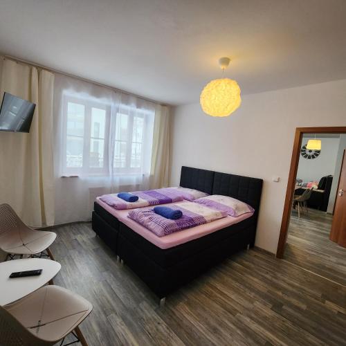 ein Schlafzimmer mit einem Bett mit violetter Bettwäsche und einem Fenster in der Unterkunft Ubytování u Maxe in Lipno nad Vltavou