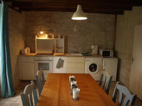 une cuisine avec une table en bois et des chaises ainsi qu'une cuisine avec une cuisinière dans l'établissement Les gîtes de la Madeleine, à La Chapelle-sur-Loire