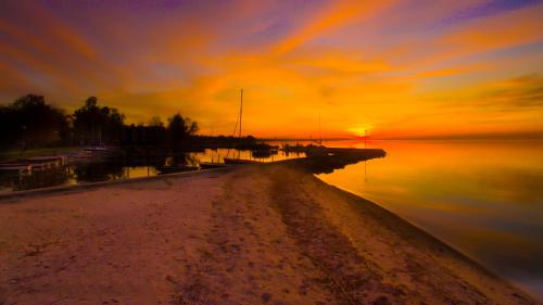 a sunset over a body of water with a dock at King Kong Kapitány Vendégház in Fonyód