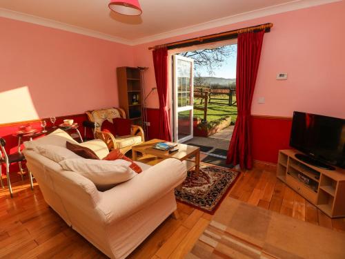 a living room with a couch and a tv at Cwtch Cowin in Banc-y-felin