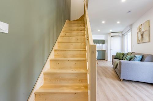 a wooden staircase in a living room with a couch at Le Green Duplex - Clim - Parking - Netflix - Nestor & Margot in Auterive