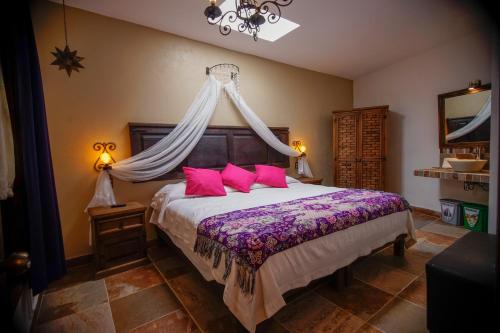 a bedroom with a large bed with pink pillows at La Escondida Hotel Boutique in Zacatlán