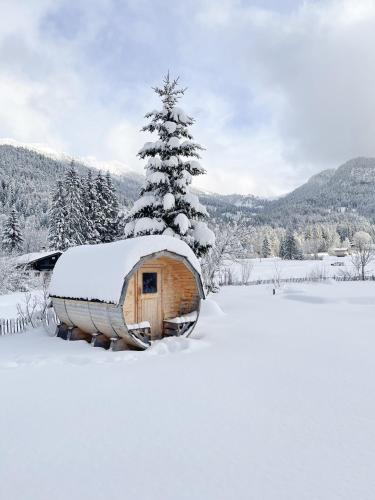 a wooden cabin in the snow with a christmas tree at Heutaler Hof - Hotel im Naturidyll in Unken