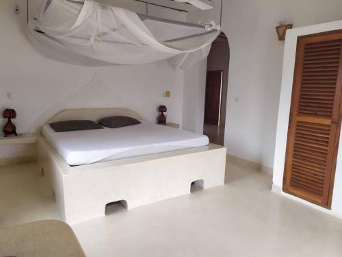 Luxury Simba House in Watamu [ ☆☆☆☆☆ ] في واتامو: غرفة نوم بسرير أبيض مع مظلة بيضاء