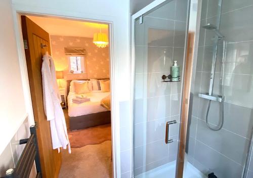 a bathroom with a shower and a bedroom with a bed at The Lodge Chester - luxury apartment for two, with free parking! in Hough Green