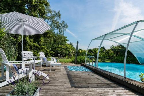 una piscina con tavolo, sedie e ombrellone di Villa Chanelle a Les Rosiers