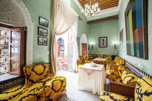 a living room with yellow furniture and a chandelier at Dar Shaeir in Rabat