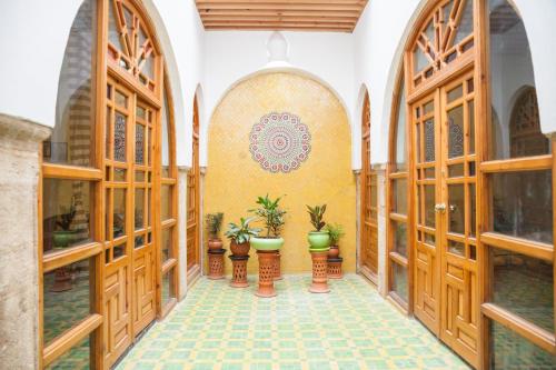 a hallway with wooden doors and potted plants at Dar Shaeir in Rabat