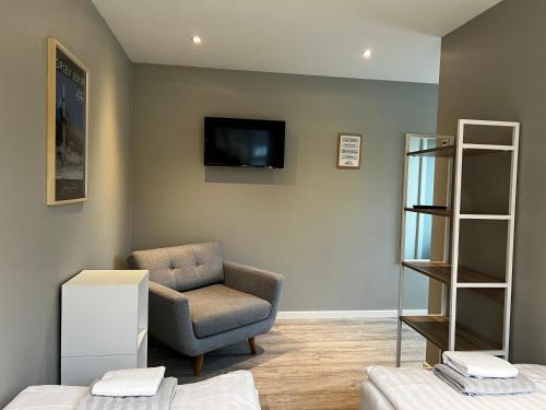 a living room with a chair and a tv on the wall at Jerup Bed & Breakfast in Jerup
