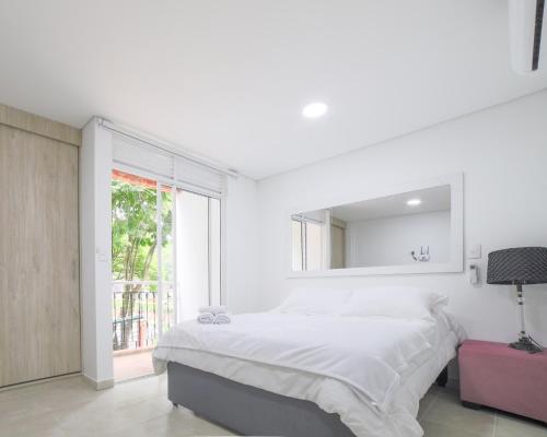 a white bedroom with a large bed and a mirror at Edificio Vida Nueva in Cali
