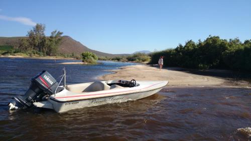 a boat sitting in the water on a river at Clanwilliam Oasis BnB Guest House - Naturism, Boating, Hiking & more in Clanwilliam