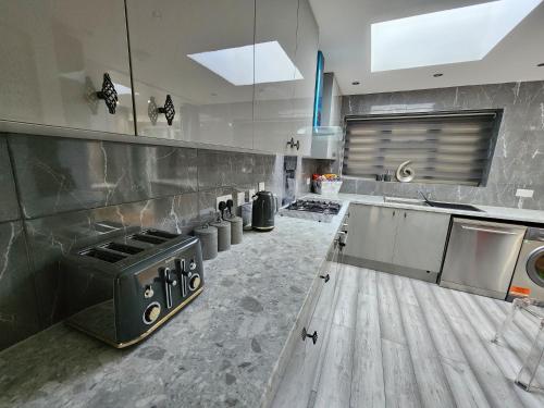 Home From Home Wembley في Preston: مطبخ كبير مع أجهزة ستانلس ستيل وأرضيات خشبية