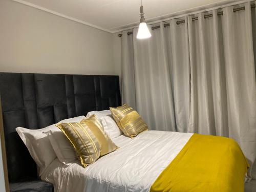 1 dormitorio con 1 cama grande con almohadas de oro en Outer Space - 1 bedroom Luxurious Apartment in Sandton, en Sandown