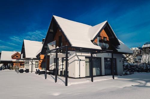 a house with a snow covered roof in the snow at Dolina Barw - całoroczne domki na wynajem in Rabka