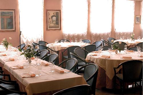 een kamer gevuld met tafels en stoelen met witte tafelkleden bij Hotel Europa in Marostica