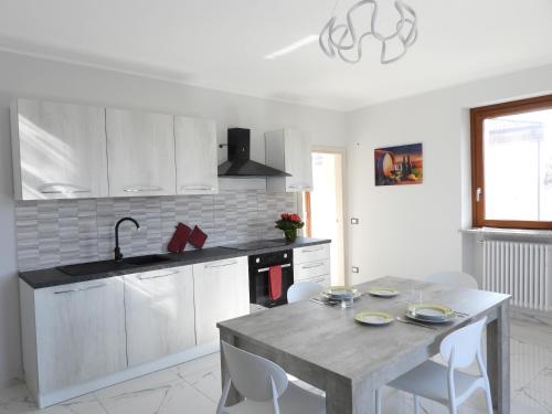a kitchen with white cabinets and a table with chairs at Roero Sunset in Govone