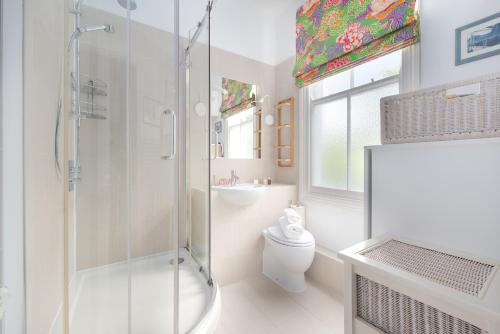 a white bathroom with a shower and a toilet at Charming flat in leafy West London by UnderTheDoormat in London