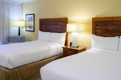 two beds in a hotel room with two lamps at Airtel Plaza Hotel in Van Nuys