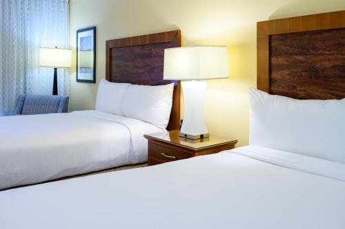 a hotel room with two beds and a chair at Airtel Plaza Hotel in Van Nuys