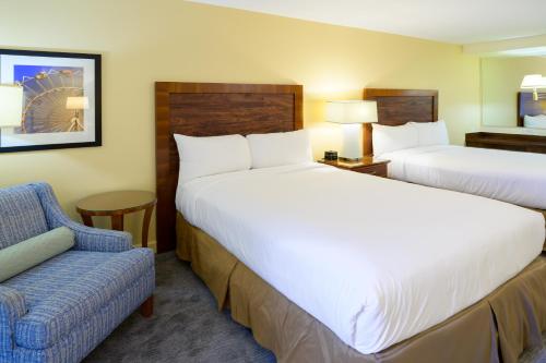 a hotel room with two beds and a chair at Airtel Plaza Hotel in Van Nuys