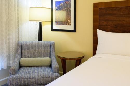 a bedroom with a bed and a chair and a lamp at Airtel Plaza Hotel in Van Nuys