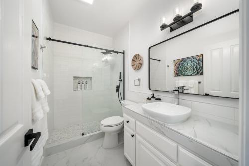 a white bathroom with a sink and a toilet at Steps Away From Pismo Beach with Poker, Foosball, FREE EV Charger, and Bikes in Oceano