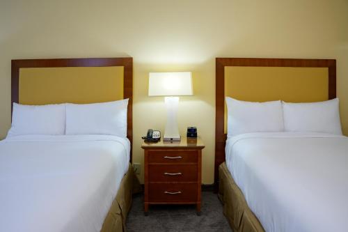 a hotel room with two beds and a phone on a night stand at Airtel Plaza Hotel in Van Nuys