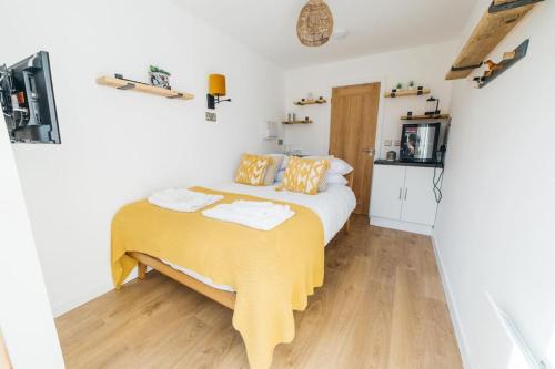 a bedroom with a bed with a yellow blanket on it at Carmen Eco-Pod / Treehouse, Close to Cabot Circus in Bristol