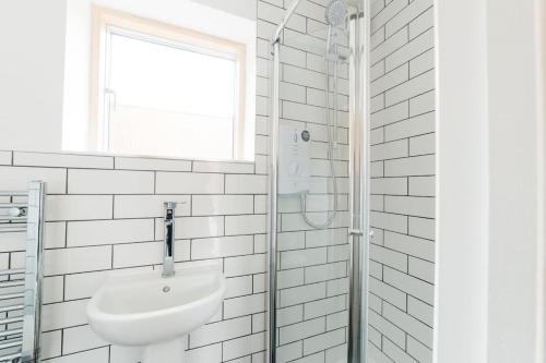 een witte badkamer met een wastafel en een douche bij Carmen Eco-Pod / Treehouse, Close to Cabot Circus in Bristol
