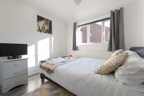 um quarto com uma cama, uma televisão e uma janela em Lovely 1 bedroom maisonette close to Airport, Town and Train Station em Luton