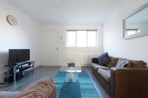 a living room with a couch and a table at Modern 1 Bed Maisonette, Contractor Friendly, Near Airport, Town Centre and Train Station in Luton