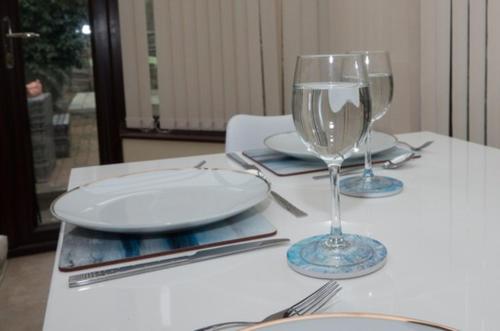 a white table with plates and glasses on it at Beautiful Bexhill Cottage with garden 3 mins walk to beach in Bexhill