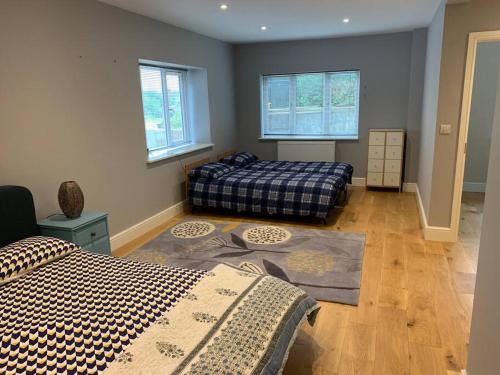 1 Schlafzimmer mit 2 Betten in einem Zimmer mit Fenstern in der Unterkunft Cosy Cottage in the heart of Black Down Hills in Yarcombe