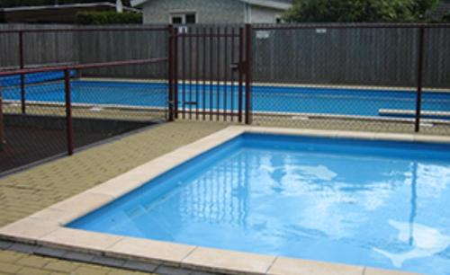 een zwembad met een hek en een blauw zwembad bij CHALET HARMONY prive WELLNESS in Putten