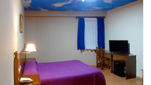 a bedroom with a purple bed and a desk at Hotel Venta El Molino in Alcázar de San Juan