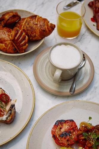 a table with plates of food and a cup of milk at Mayfair House Hotel & Garden in Miami