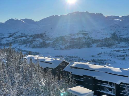 a building covered in snow with mountains in the background at Astonishing Mountain Lodge at the top of Gaustablikk, 25m2 west facing terrace, 3 bedrooms in Gaustablikk