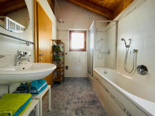 uma casa de banho com um lavatório, um chuveiro e uma banheira em Apartment Oberhauserhof em Falzes