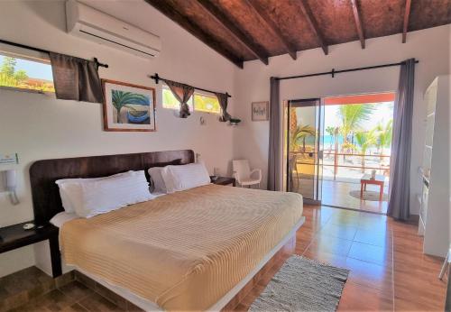 a bedroom with a large bed and a sliding glass door at Hotel Punta del Norte Bungalows in Canoas de Punta Sal