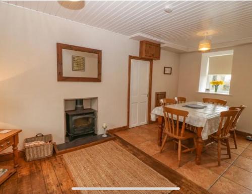 a dining room with a table and a fireplace at Tyn Lon in Aberdaron